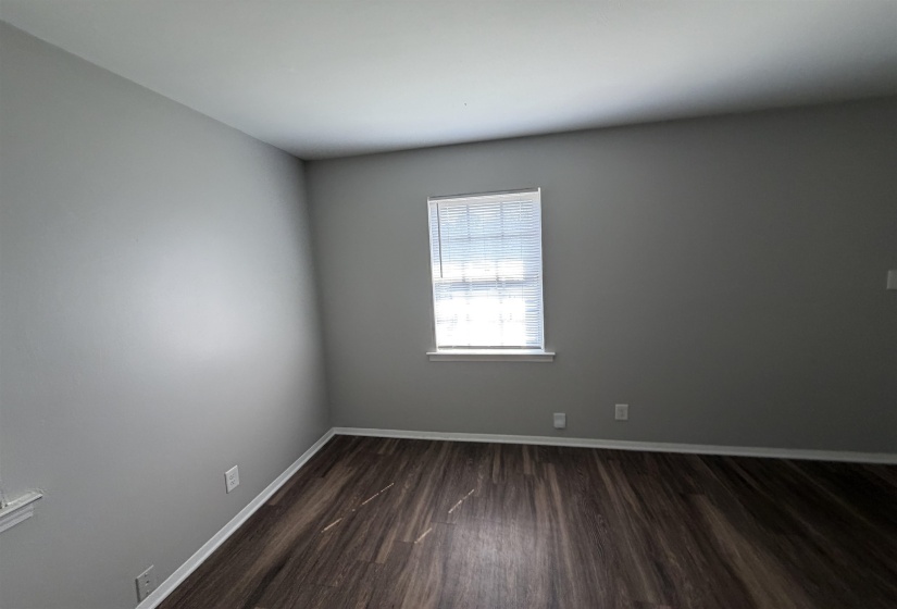 Room featuring wood-finish flooring, light gray wall paint, white baseboards, and a window with blinds