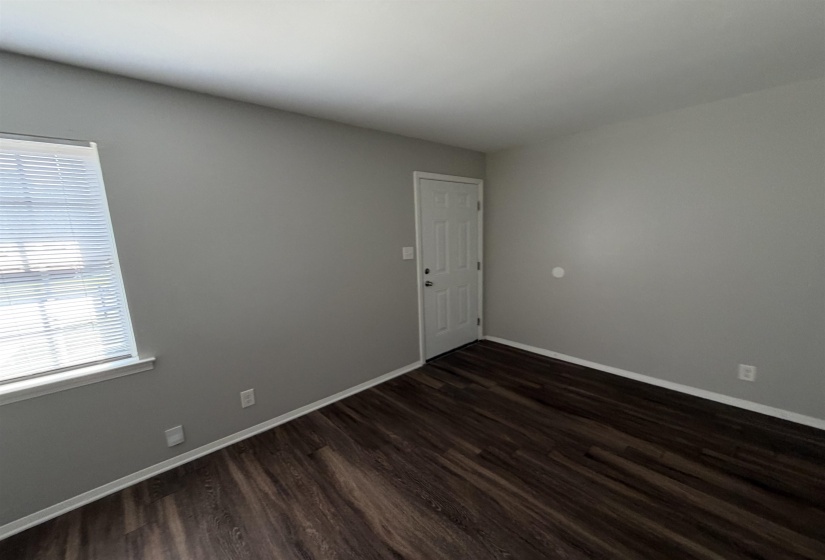 Interior room featuring wood-finish flooring, light gray wall paint, and white baseboards