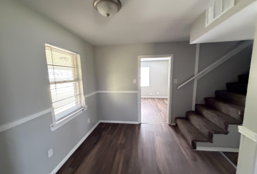 Entryway featuring wood-finish flooring, light gray walls with white chair rail molding, and a window with blinds