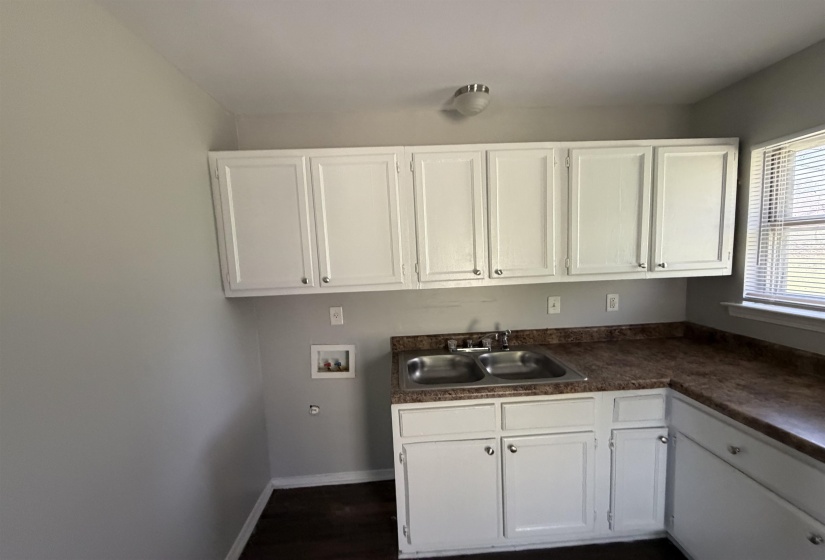 Kitchen area featuring white cabinetry, a double basin stainless steel sink, and wood-finish countertops