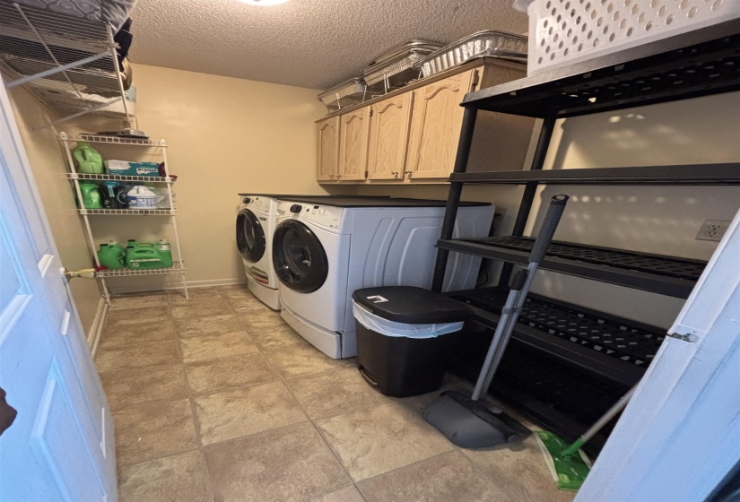 Utility room featuring light-toned cabinetry and tiled flooring