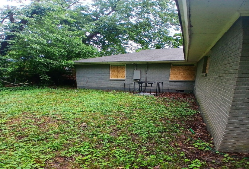 Rear exterior featuring gray brick siding and a dark shingle roof