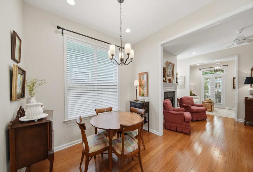 Dining area featuring a contemporary chandelier, wood-finish flooring, and a large window with blinds