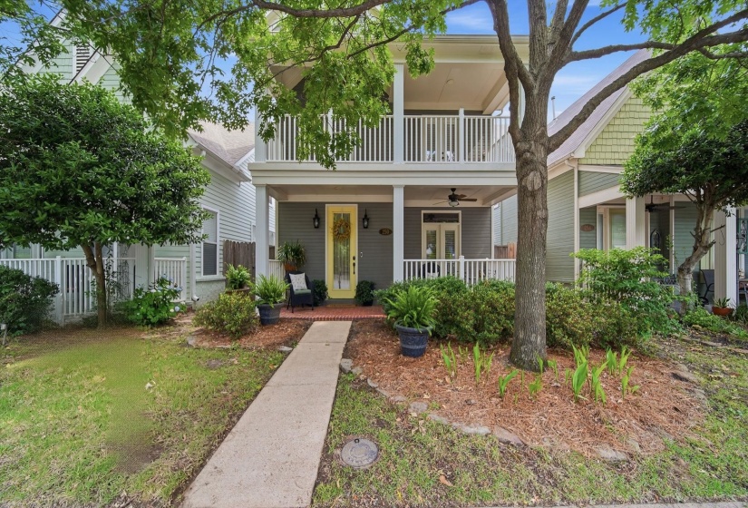 Two-story home with a prominent yellow front door, covered porch, and upper-level balcony