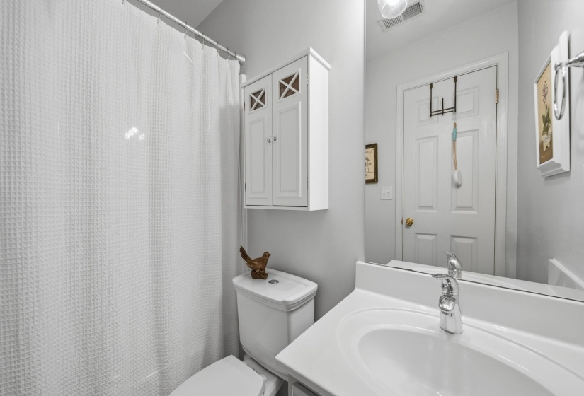 Bathroom featuring a white vanity with an integrated sink, polished chrome faucet, wall-mounted mirror, and a built-in storage cabinet