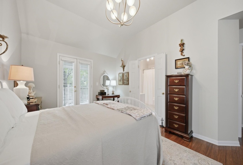 Vaulted ceiling with a contemporary light fixture, wood-finish flooring, and French doors featuring blinds