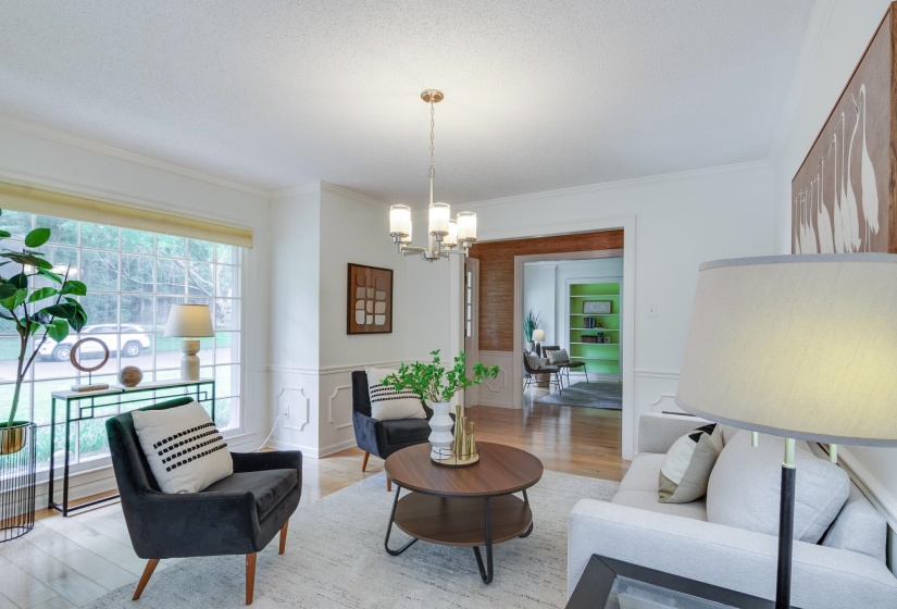 Living area featuring a large picture window, wood-finish flooring, crown molding, and wainscoting