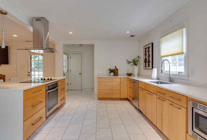 Modern kitchen featuring light wood cabinetry, white countertops, and stainless steel appliances