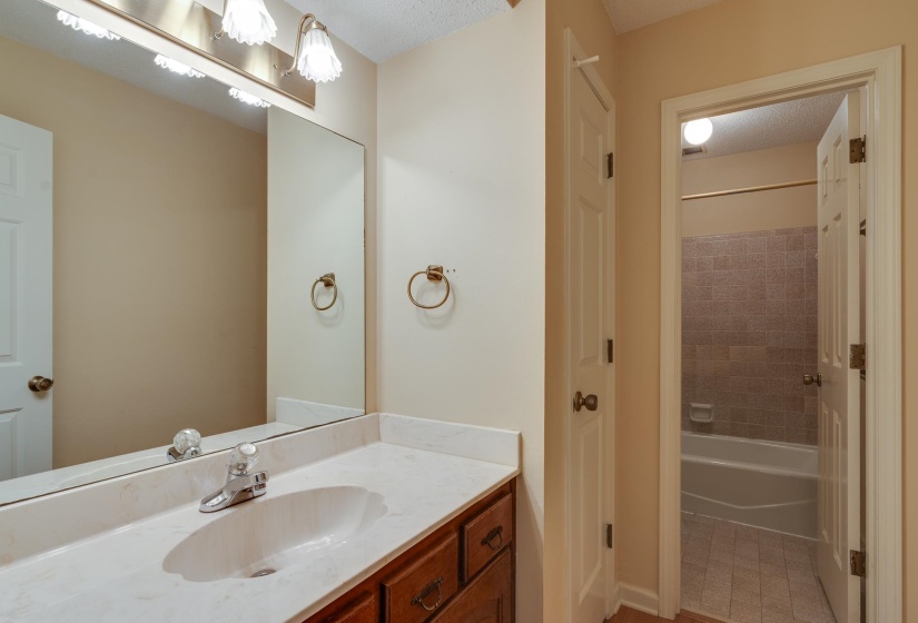 Bathroom vanity with a white countertop and integrated sink, chrome faucet, and wood-finish cabinetry