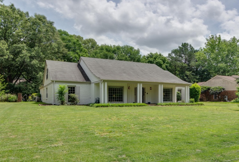 White brick exterior with a dark shingle roof, featuring a covered front porch with substantial columns