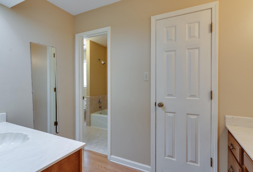 Bathroom featuring dual vanity areas with white countertops, wood-finish cabinetry, and a full-length mirror