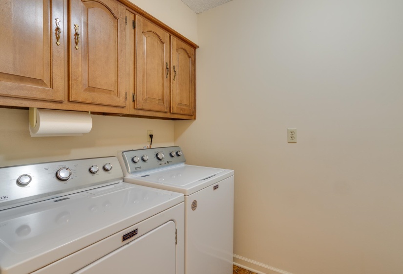Laundry area with wood-finish upper cabinetry and a textured ceiling