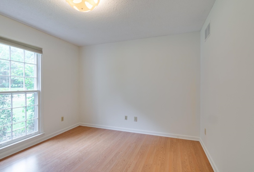 Bright interior space featuring wood-finish flooring, white walls, and a large multi-pane window