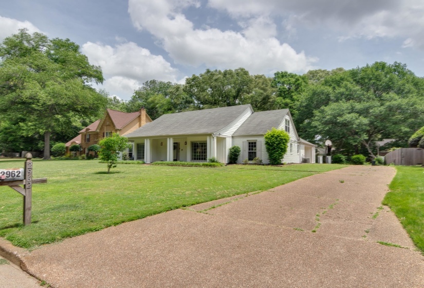 Traditional-style home featuring a covered front porch with white columns, white siding, and a gray shingle roof