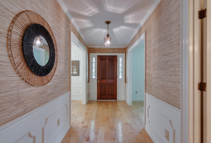 Entryway featuring wood-finish flooring, wainscoting, and textured wallcovering