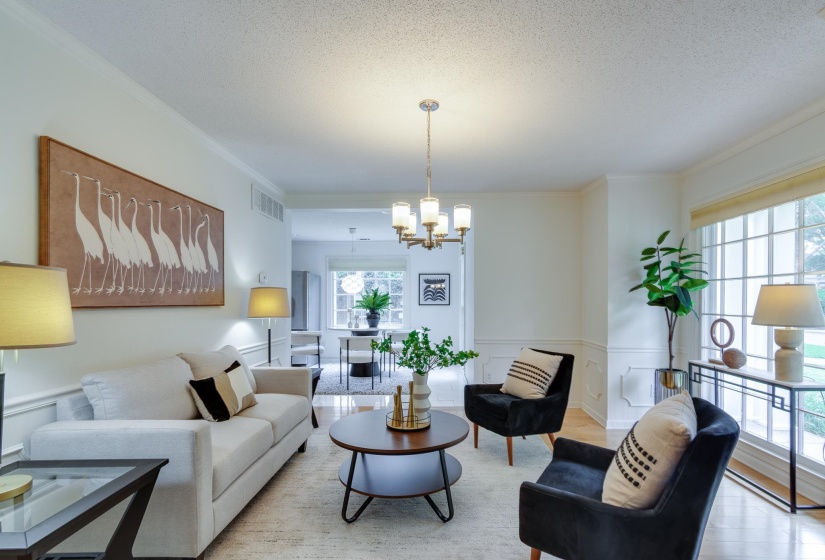 Bright living area featuring crown molding, wainscoting, a multi-pane window, and wood-finish flooring