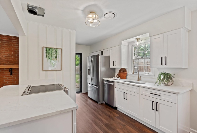 Modern kitchen featuring white shaker cabinetry, stainless steel appliances, white countertops, and wood-finish flooring