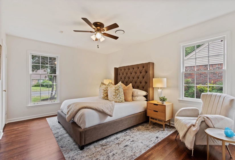 Well-lit interior space featuring rich wood-finish flooring, white walls, and a ceiling fan with integrated lighting