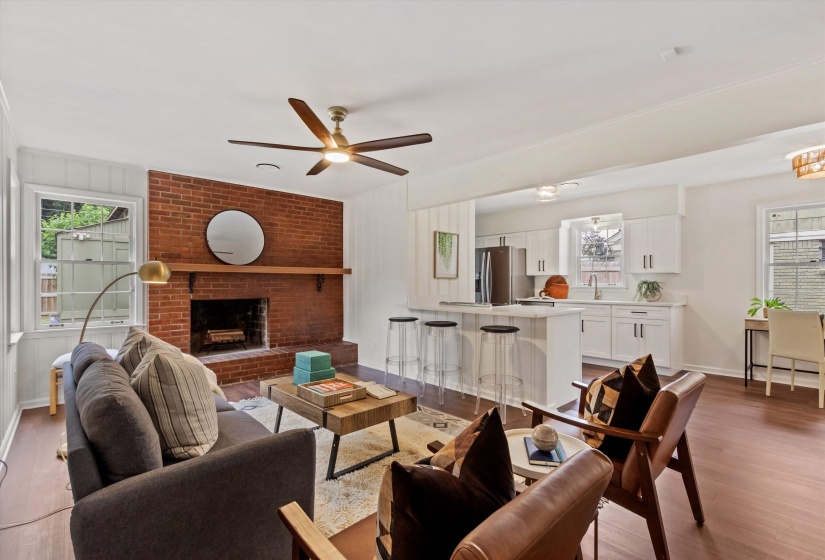 Living area featuring a brick fireplace with wood mantel, a ceiling fan, and wood-finish flooring