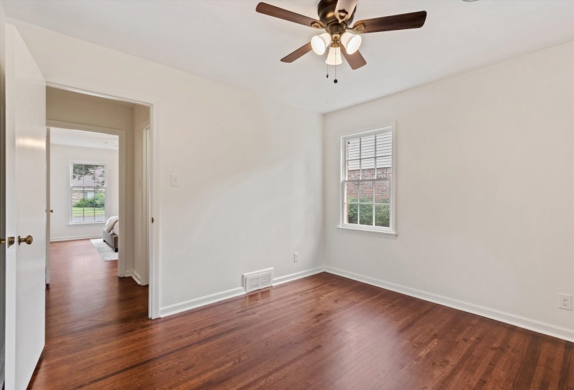 Room featuring rich wood-finish flooring, white painted walls, and white baseboards