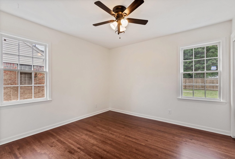Bright room featuring rich wood-finish flooring, white walls, and a ceiling fan with integrated lighting