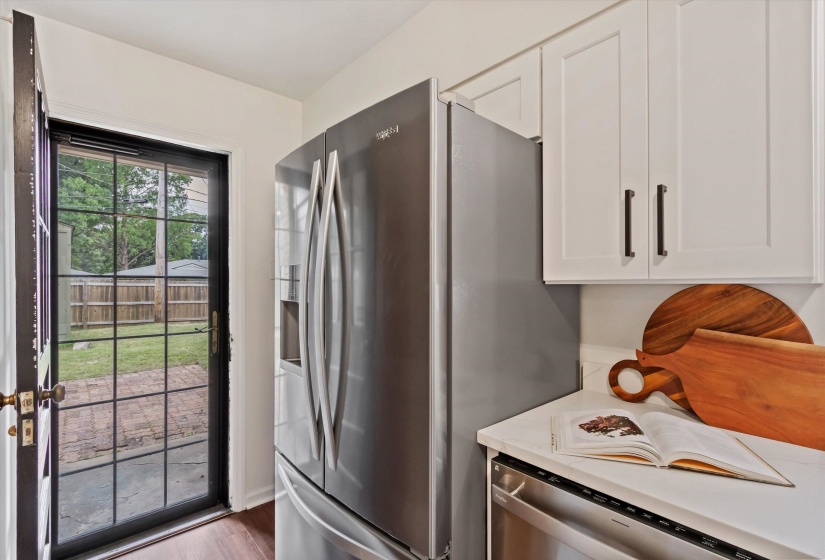 Kitchen featuring stainless steel French door refrigerator, white shaker-style cabinetry with dark hardware, a white countertop, and wood-finish flooring