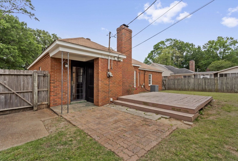 Brick exterior featuring a wood deck and an outdoor patio with brick pavers
