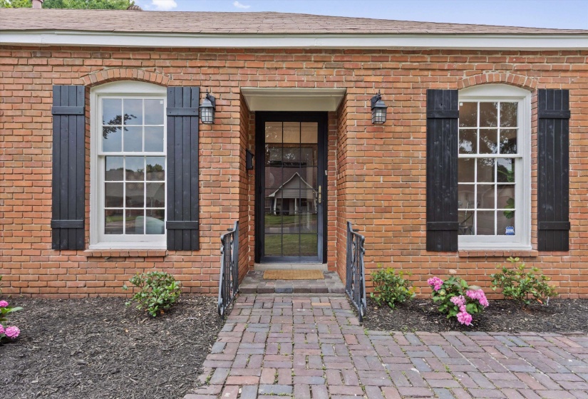Brick exterior with a central entry door featuring transom and sidelight windows