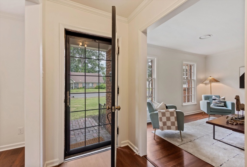 Entryway featuring a grid-patterned glass storm door, brick porch, and wood-finish flooring