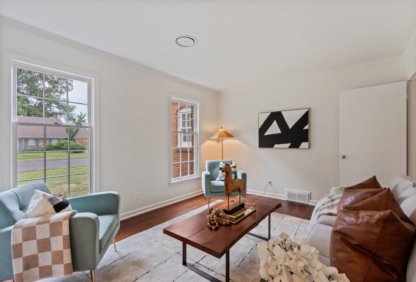 Living area featuring hardwood flooring, white walls, and crown molding