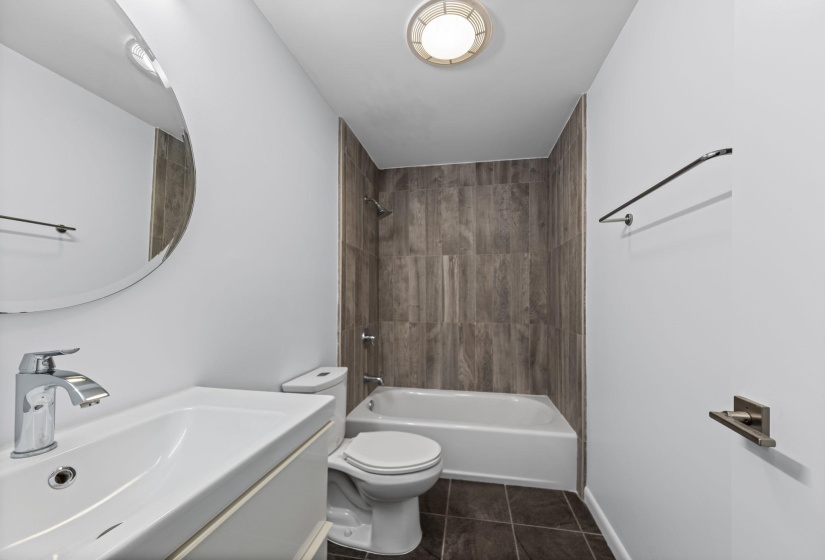 Bathroom featuring a white vanity with integrated sink, chrome faucet, and a round wall mirror