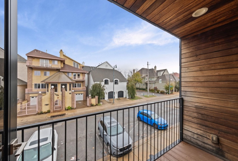 Balcony featuring wood-finish siding and ceiling, a recessed light fixture, and black metal railings overlooking a residential street