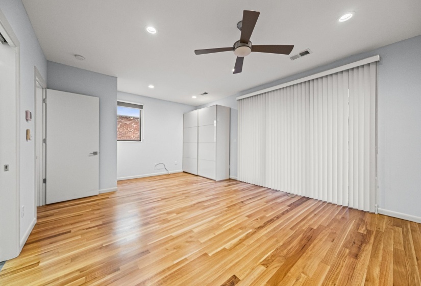 Spacious room featuring wood-finish flooring, a contemporary ceiling fan, and recessed lighting