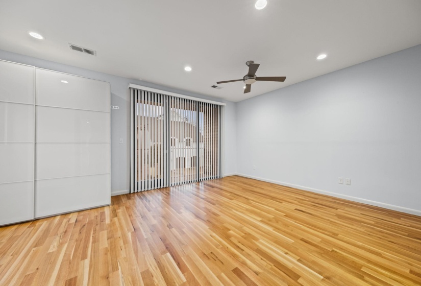 Hardwood flooring extending throughout, complemented by a contemporary ceiling fan
