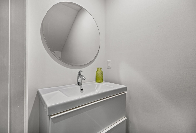 Modern vanity with an integrated basin sink, chrome faucet, and a large circular mirror