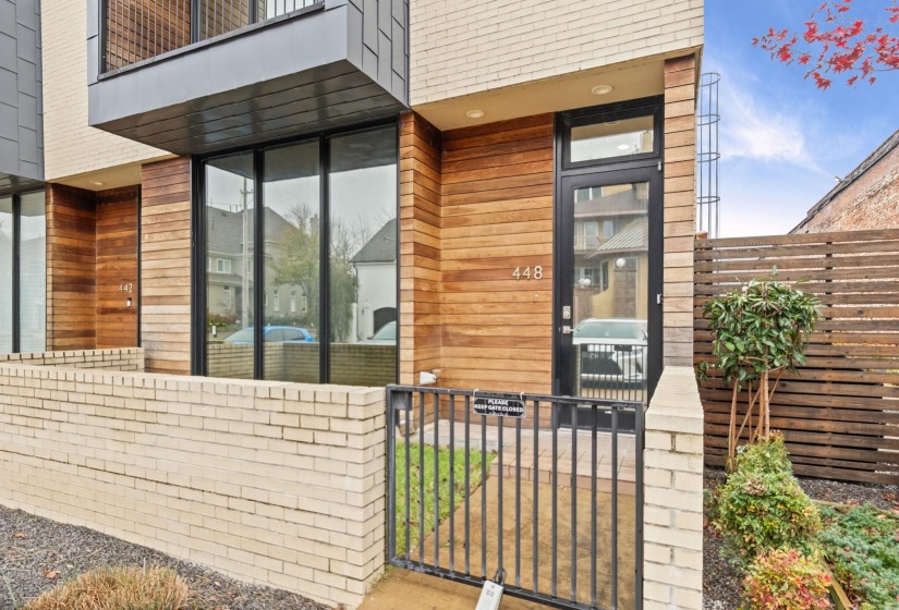 Contemporary exterior featuring a wood-panel accent wall, full-light entry door, and large floor-to-ceiling windows
