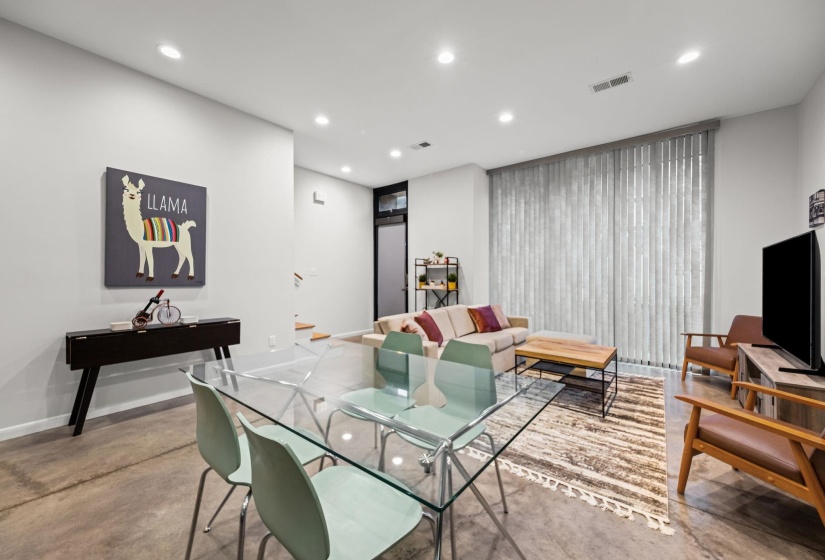Open-concept room featuring concrete flooring, recessed lighting, and a large window with vertical blinds