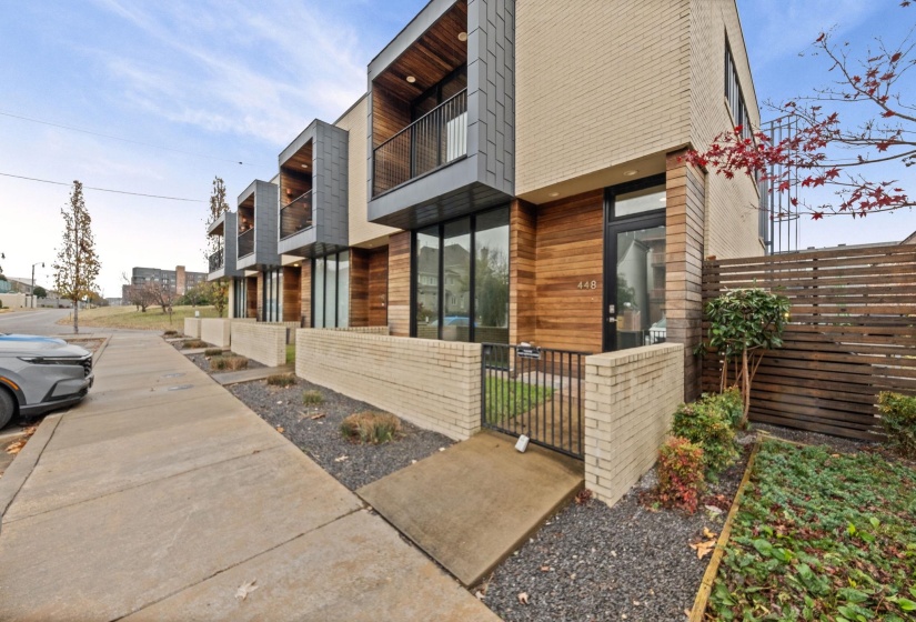 Contemporary townhome exterior featuring light brick, wood-paneled accents, and large windows