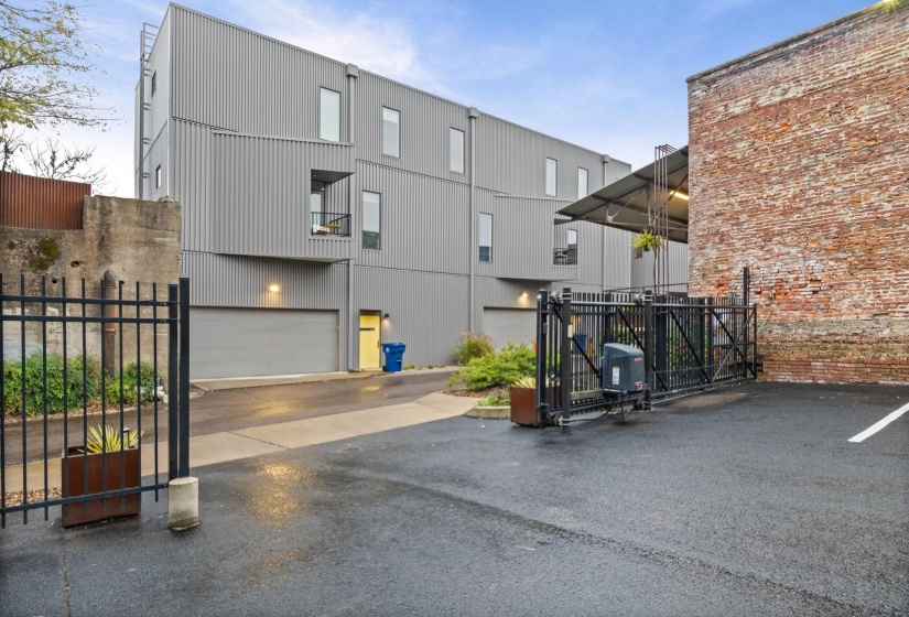 Modern industrial exterior featuring corrugated metal siding, multiple windows, a private balcony, and an attached garage