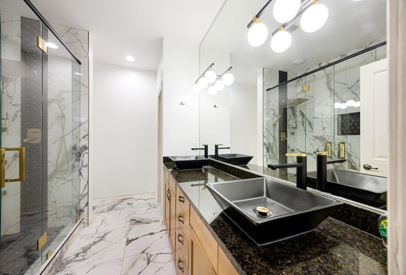 Full bath with a marble finish shower, double vanity, and light marble finish flooring