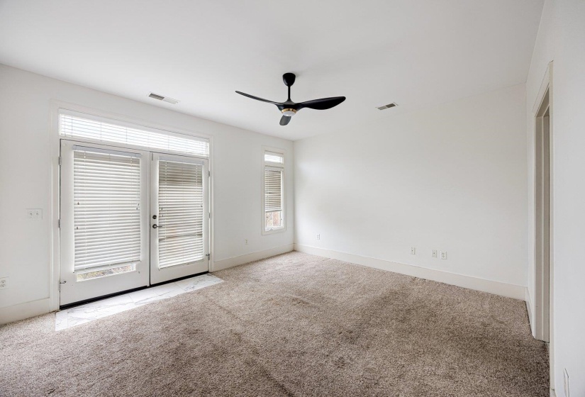 Empty room featuring healthy amount of natural light, a ceiling fan, light colored carpet, and french doors
