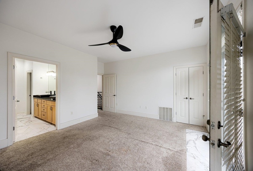 Unfurnished bedroom featuring light carpet, a ceiling fan, and ensuite bathroom