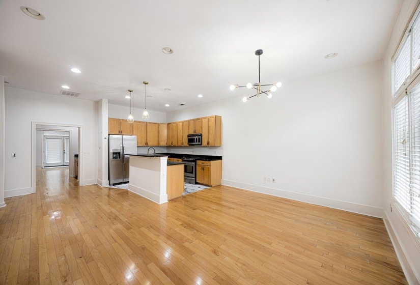 Kitchen with dark countertops, open floor plan, a center island with sink, stainless steel appliances, and light wood-type flooring