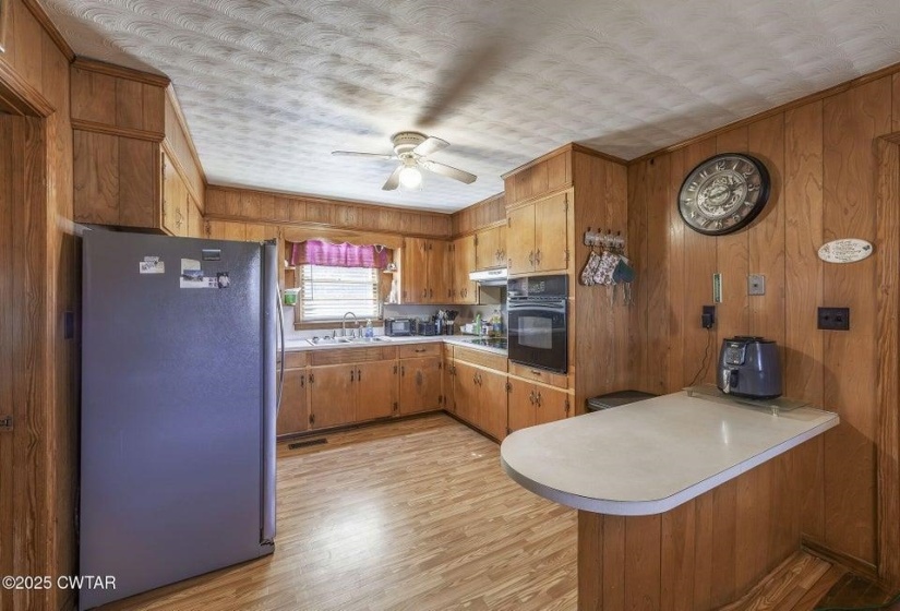 Kitchen featuring wood-paneled walls, wood-finish flooring, and built-in wood cabinetry