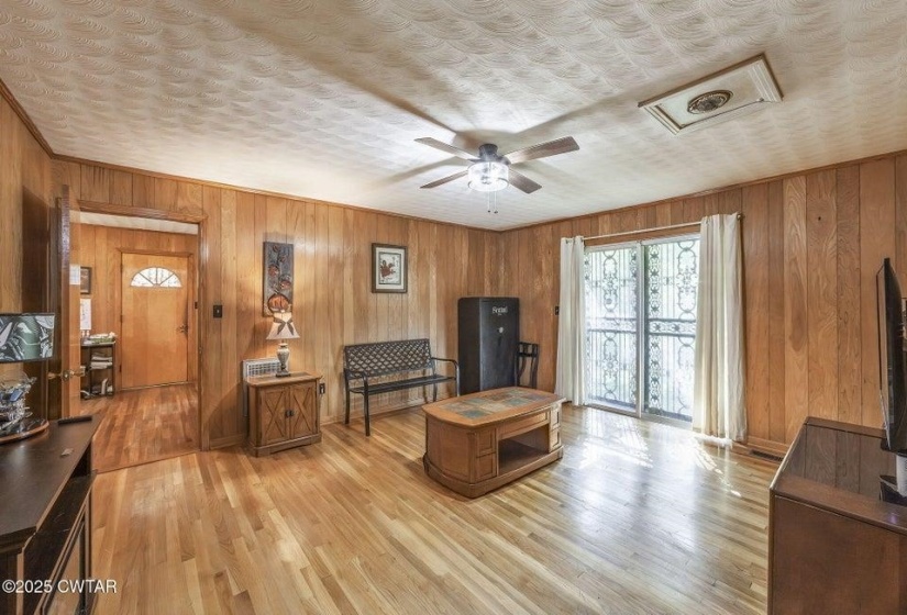 Living area featuring wood-finish flooring, wood paneling, and a textured ceiling