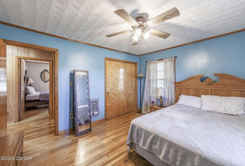Bedroom featuring wood-finish flooring, a ceiling fan with integrated lighting, and a light-colored wood headboard
