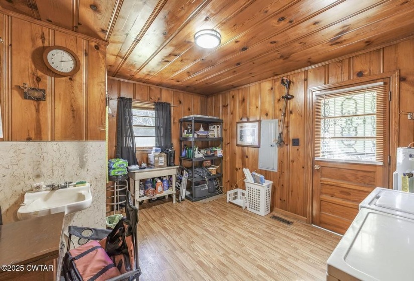 Utility space featuring natural wood paneling, wood-finish flooring, and a built-in utility sink