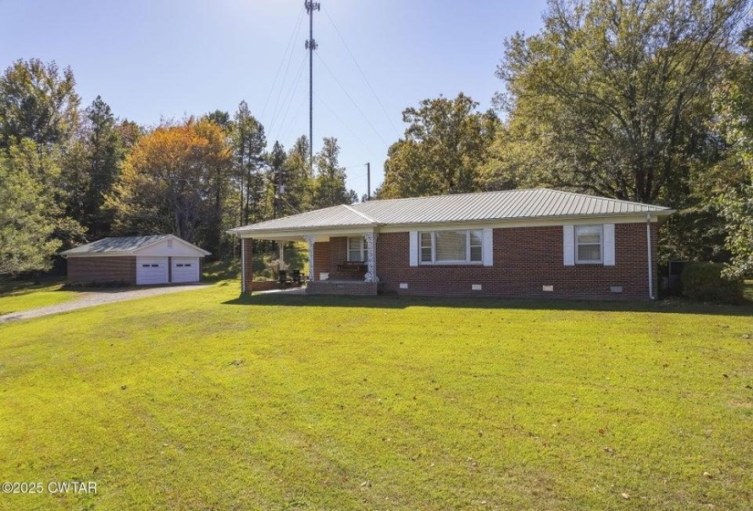 Brick ranch-style residence featuring a covered front porch, white window shutters, and a metal roof