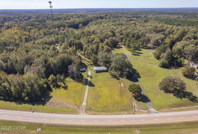 Expansive property featuring a single-story residence, two separate driveways, and a substantial wooded area
