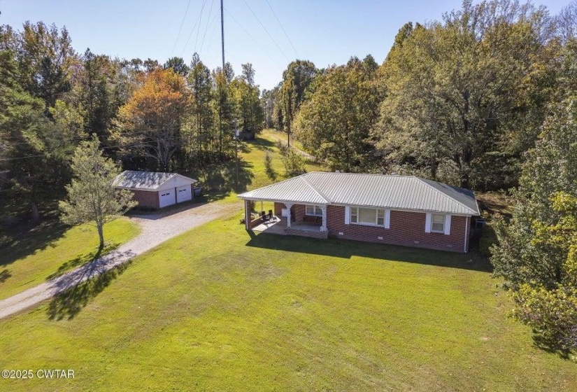 Brick ranch-style home featuring a metal roof and an expansive front lawn